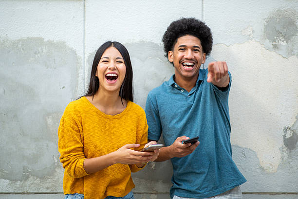 istock cheerful young couple with mobile phone and pointing finger 2206127506