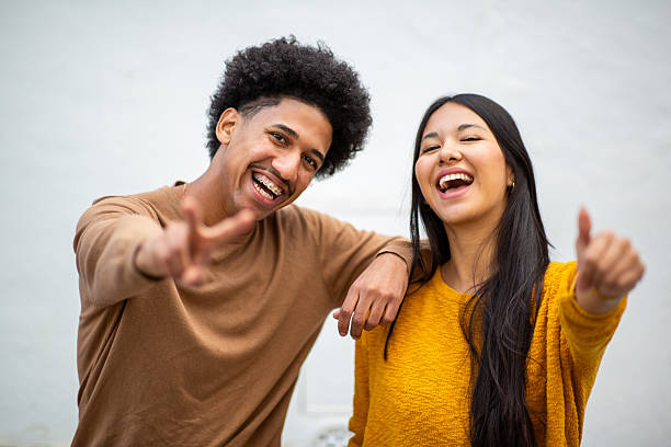 istock happy young couple with cheerful smiles and peace gestures. 2206127513