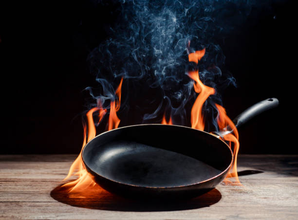 Black cooking pan with flames placed in kitchen on dark background table.