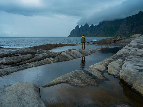 Serene man exploring the seaside Lofoten Island in stormy weather. Shot on medium format camera with immense quality of details