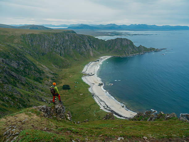 istock Man standing at the cliff looking at Lofoten Islands from above 2206131248