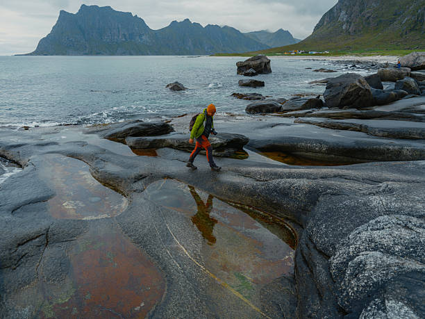 Serene man walking in solitude on the beach in Norway and looking at scenic view of the Atlantic ocean