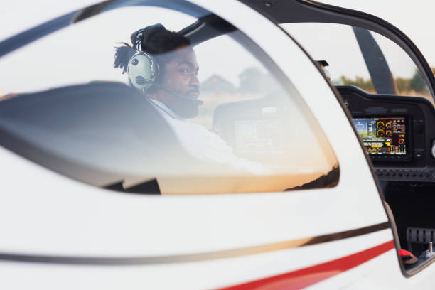 African American airplane pilot sitting in a private jet and preparing it for a take-off