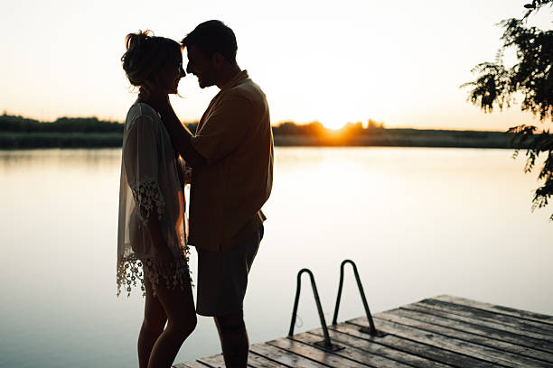 Young couple sharing a tender moment on a pier at sunset