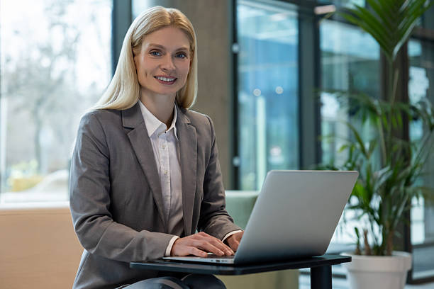 istock Smiling attractive employee using laptop on couch for online work 2206139756