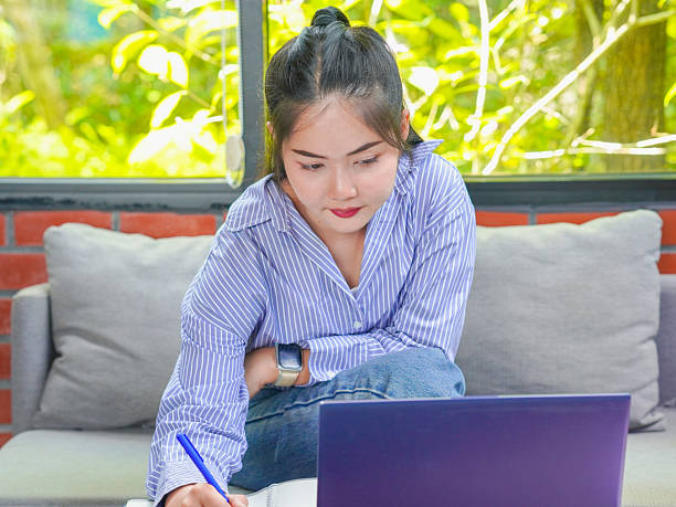 istock Asian businesswoman remote work using laptop, phone, notebook to write notes and plan roadmap for small business. 2206156009