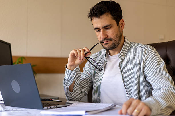 istock Pensive businessman working from home office reviewing documents and using laptop 2206157854