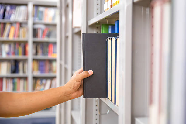 istock Book and library, close up hand choosing and picking books from bookshelf in library. Concepts of reading textbook and school for student knowledge education or study and learning. 2206158023