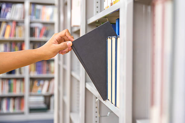 istock Book and library, close up hand choosing and picking books from bookshelf in library. Concepts of reading textbook and school for student knowledge education or study and learning. 2206158026