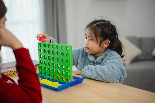 Child Concentrating on Board Game While Having Fun with Asian Family Indoor Activity at Home