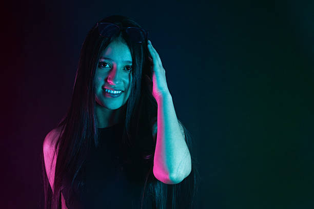istock young Latina college student woman smiling while placing a hand on her head, posing in studio light. 2206164246