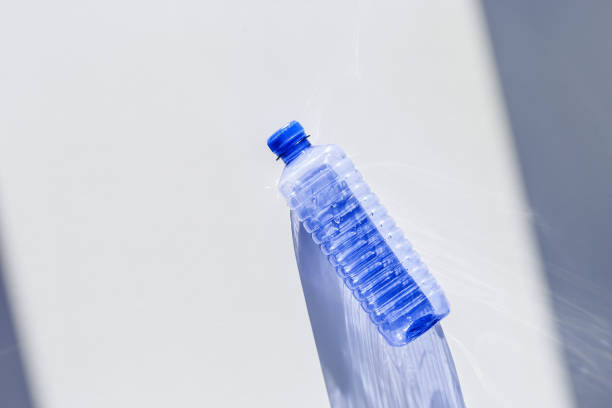 istock Transparent plastic bottles with blue caps and sun shadows on light background. Top view Water bottles at natural light. Themes of recycling, sustainability, water conservation, minimal style 2206167550