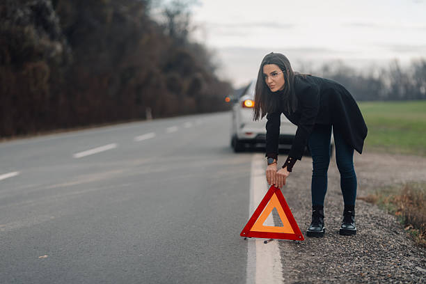 istock Businesswoman placing warning triangle on road after car breakdown 2206169978
