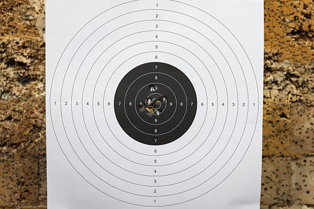 Shooting with a 45 Caliber Pistol at a Target: Capturing Precision and Skill on a Paper Target Background Pierced with Bullets at the Shooting Range.Close up photo
