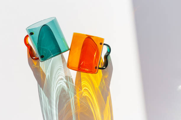 istock Orange and green Glass Mugs with bright sunlight Shadows, transparent cups casting dynamic, vibrant lights reflections and shadows on light white, creative aesthetic top view, minimal style, closeup 2206170763