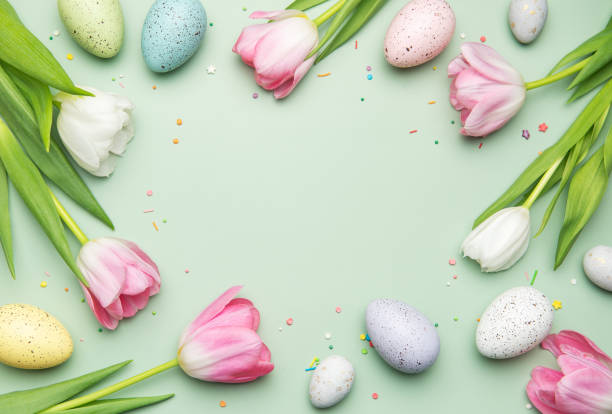 istock Easter eggs and tulips forming a frame on a pastel green background 2206171067