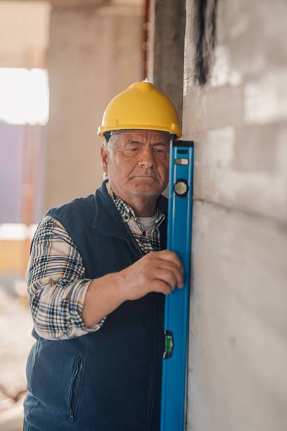 istock Senior construction worker using spirit level on wall at building site 2206171945