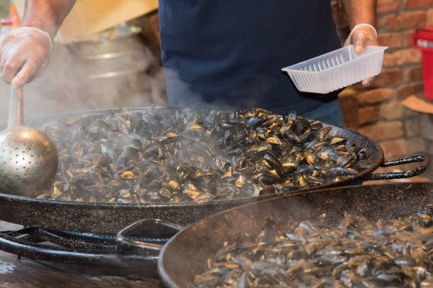 Mussels cooking in two large frying pans