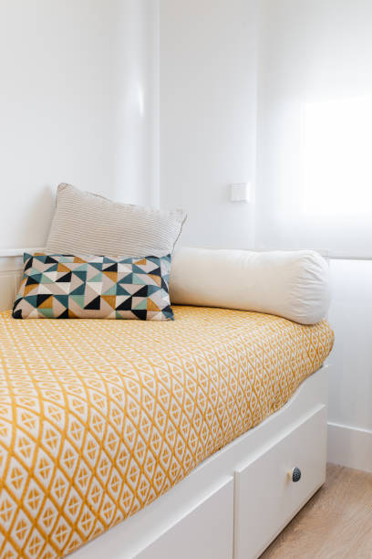 istock Bright bedroom with wooden bed, yellow patterned bedspread and comfortable cushions 2206184021