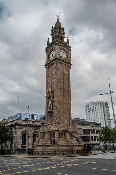 Belfast, Northern Ireland -  August 4, 2023: The Albert Memorial Clock tower in Belfast is a Gothic Revival sandstone structure with an ornate spire and visible clock face, standing prominently at a street corner with modern buildings in the background
