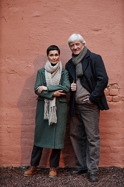 istock Portrait of Elderly Couple Standing Against Brick Wall 2206189729