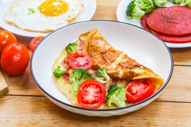 a dish of omelet, fried egg and vegetables on a wooden table as a breakfast menu