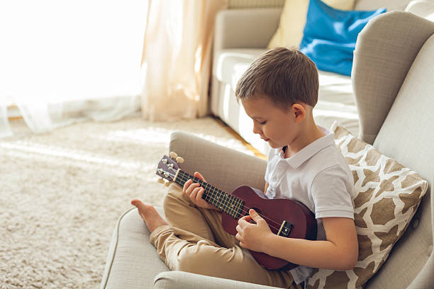 istock Little boy plays the ukulele. Home teaching music. Quarantine. 2206190254