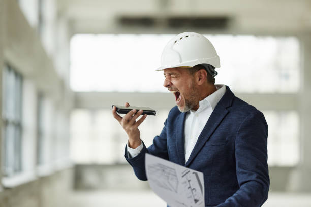 istock Frustrated male architect talking on conference phone at construction site. 2206191311