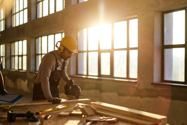 Male carpenter cutting wood plank at construction site.