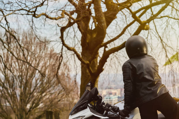 A young woman rides her motorcycle along a picturesque countryside road, enjoying the open air and freedom of the journey. She takes a break to admire the stunning landscape, reflecting on her achievement of purchasing a new bike. Dressed in stylish motorcycle gear, including a black riding suit and sometimes a denim jacket, she exudes confidence and adventure. The images capture the essence of independence, exploration, and the joy of the open road.