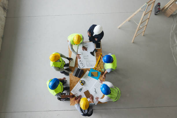 istock Above view of architect and manual workers working on plans at construction site. 2206192847