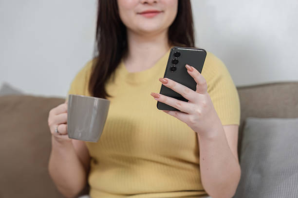 istock Coffee Break and Smartphone Communication. A woman enjoying a coffee while checking her smartphone at home. 2206197487