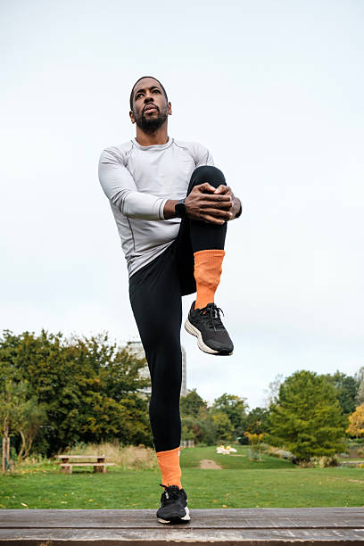 istock Young black athlete stretching legs after running in park 2206199064
