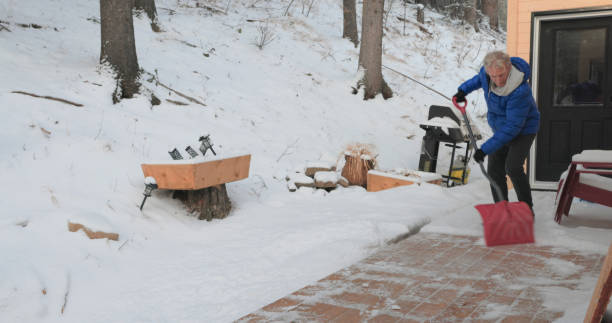 Mature man shovels fresh snow from deck of chalet, Canadian Rockies