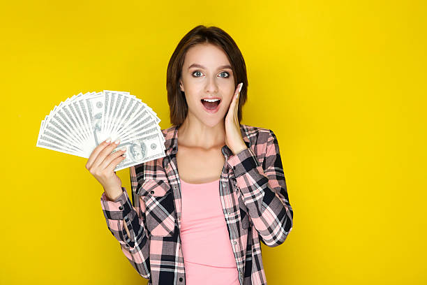 istock Young woman holding dollar banknotes on yellow background 2206205052