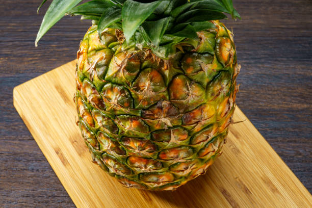 Fresh pineapple and cutting board on wooden table