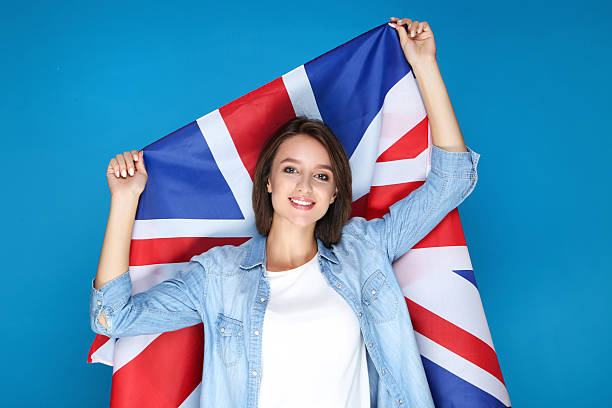 istock Beautiful young woman holding british flag on blue background 2206206178