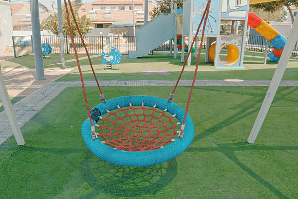 Round swing hanging still in a deserted playground during a sunny summer day