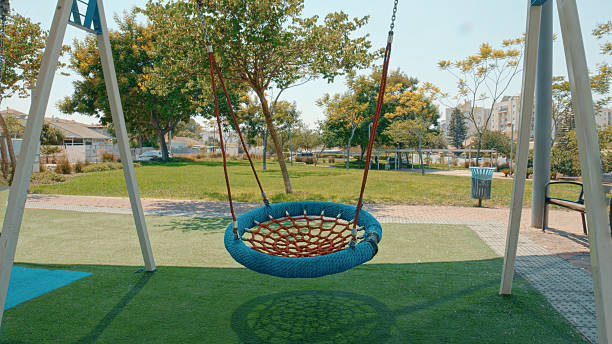 istock Empty round swing hanging in a playground during a sunny day 2206208199