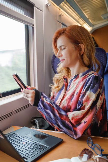 istock Beautiful woman riding intercity day train, smiling and using smart phone 2206213007