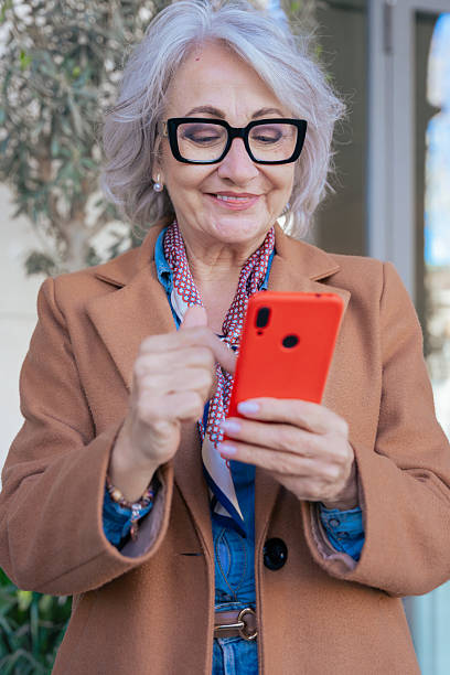 istock Smiling Caucasian senior woman using smartphone outdoors in urban environment 2206214116