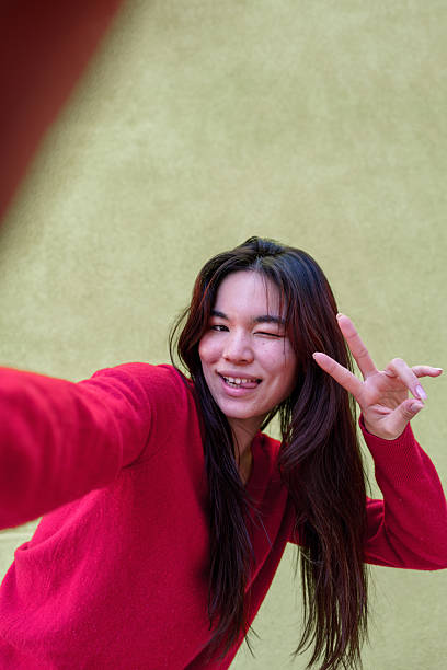 istock Young woman taking a selfie while winking and making peace sign 2206218164