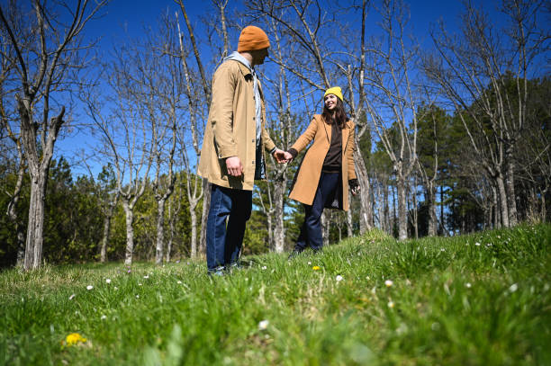 Young couple holding hands while walking in a park during early spring