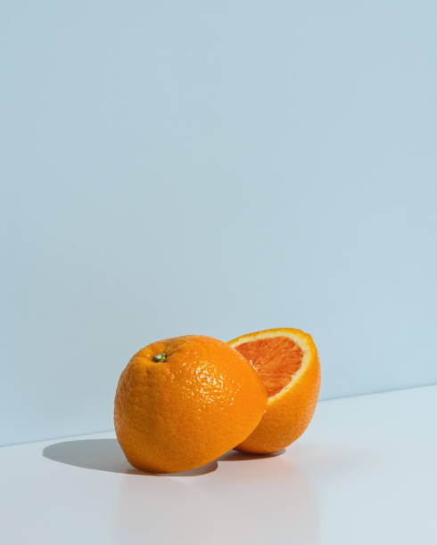istock Bright fresh orange cut in half on a minimal blue background, conveying freshness, healthy lifestyle, and vibrant summer mood. 2206224247