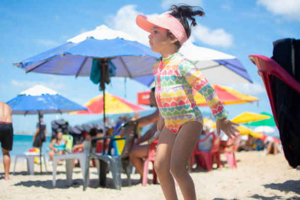 Adorable little girl playing on a sandy beach on a sunny day.Happy with her family.