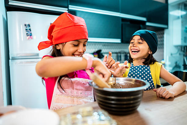 istock Sisters playing and preparing cake in the kitchen 2206228957