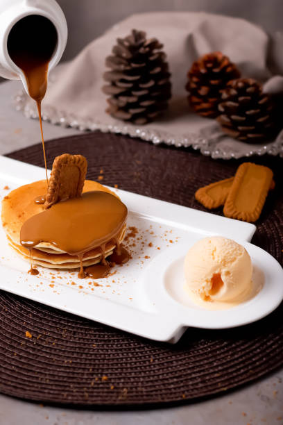 Pancake with lotus biscuit, hot chocolate and Ice Cream Scoop served in plate isolated on mat side view of Delicious dessert treat