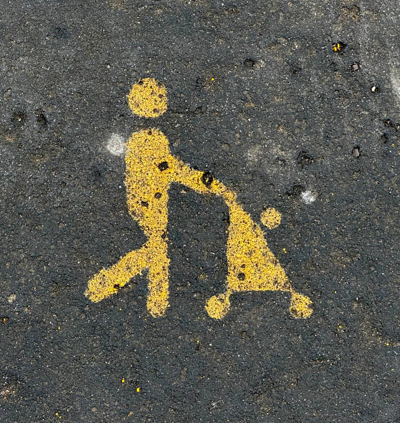 Baby buggy icon in black on yellow pavement indicating parking spot for visitors with small children