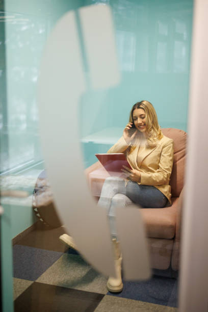istock Young businesswoman talking on mobile phone in silent office booth 2206234292