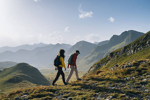 istock Couple hike across mountain meadow at sunrise 2206235785